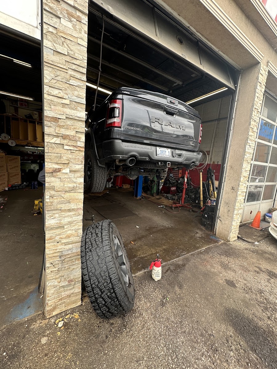Pickup truck raised on a lift inside the bay with a tire on the floor in front