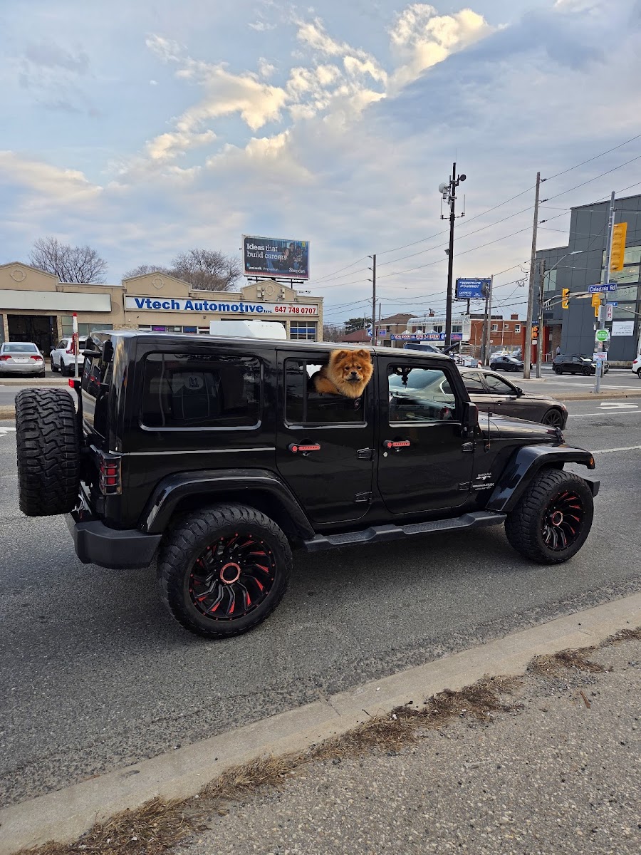 Black Jeep Wrangler with custom black-and-red rims parked outside the shop on Lawrence Ave W